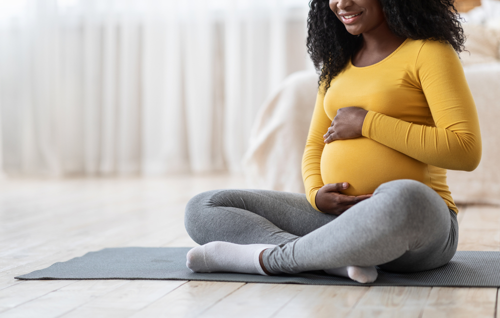 pregnant woman sitting on yoga mat on floor.