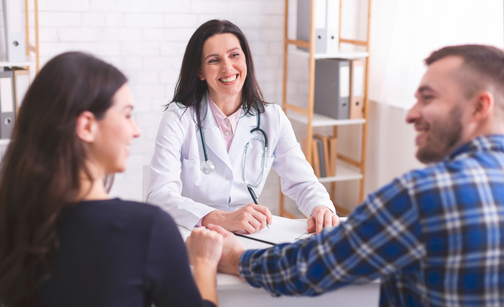 man and woman talking to doctor smiling.