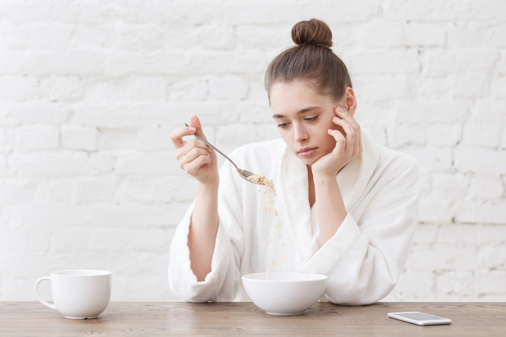 woman holding spoon in her hand but not wanting to eat.