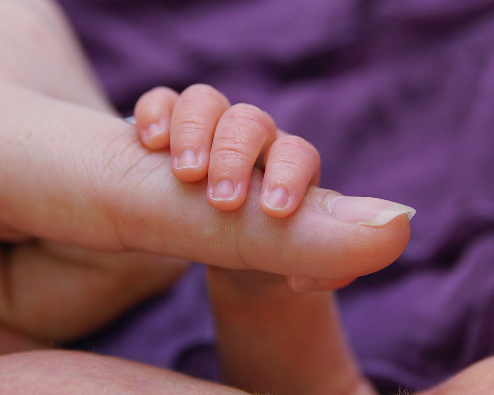 mom holding babies hand.